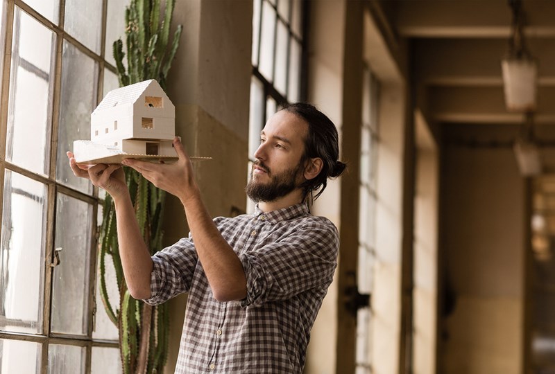 man inspecting miniature model home in loft apartment
